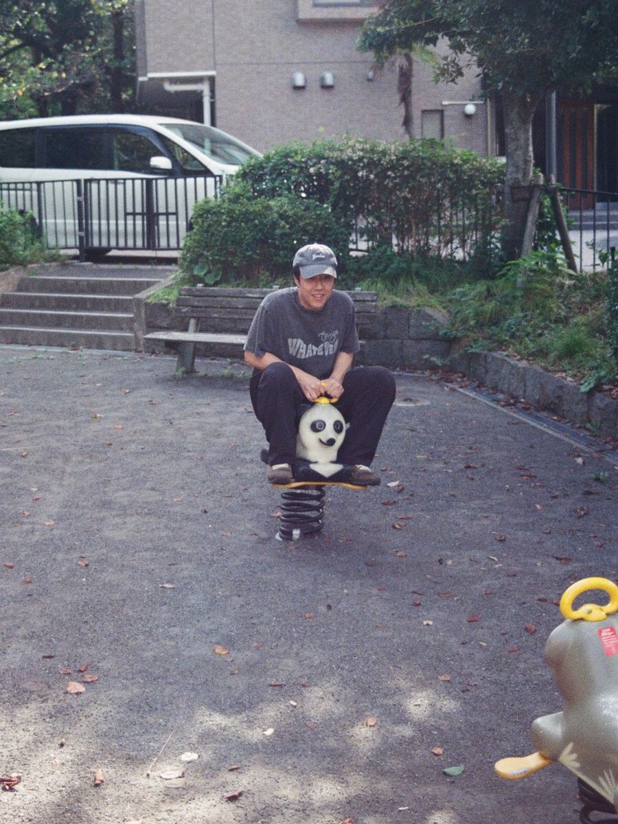 Luozhou Wang sitting on a panda spring rider in a neighborhood playground